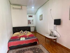 a bedroom with a bed and a small table at Mai Chenang Guesthouse in Pantai Cenang