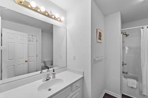 a white bathroom with a sink and a mirror at 5 Bedroom Beach House 12 Minutes from Beach w/ Firepit & BBQ Grill in Nags Head