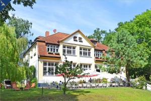 una grande casa bianca con tavoli e sedie di fronte di Waldsiedlung Waldhaus App 4.1 a Korswandt