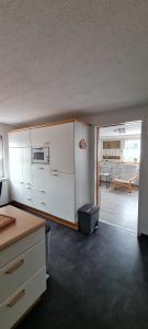 cocina con armarios blancos y sala de estar. en Ferienwohnung, Urlaub im Frankenwald en Konradsreuth