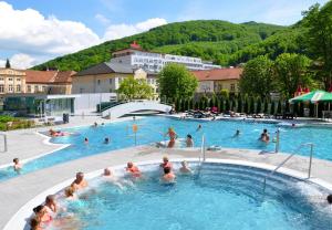 Eine Gruppe von Menschen schwimmt in einem Schwimmbecken in der Unterkunft Hotel Margit in Trenčianske Teplice