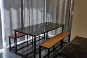 a table and two benches in front of a window at All Seasons, luxury villa in Kotagiri