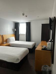 a hotel room with two beds and a window at Redwings Lodge Birmingham in Oldbury