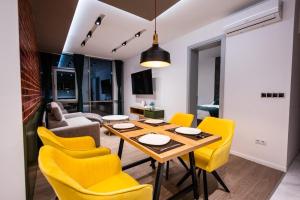 sala de estar con mesa y sillas amarillas en DMS Apartments & Suites Sarajevo, en Vogošća