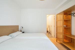 a bedroom with a large white bed and wooden shelves at Iria Gardens in Padrón