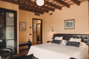 a bedroom with a large white bed with black pillows at Hotel Vall de Bas in Joanetes
