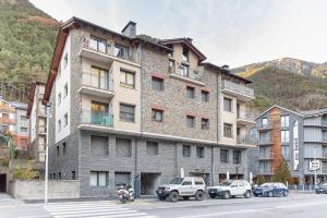 un gran edificio de ladrillo con coches estacionados frente a él en AndBnB I 3 Habitaciones con Terraza y Parking en Ordino