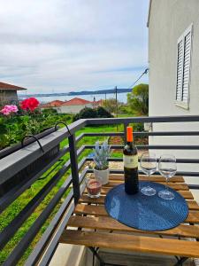 een fles wijn en twee glazen op een tafel op een balkon bij Room Ela in Donji Seget