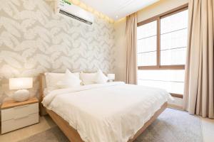 リヤドにあるAmber Hospitality - Al Izdiharの大きな白いベッドと窓のある寝室