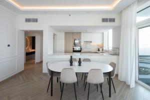 Il comprend une cuisine et une salle à manger avec une table et des chaises blanches. dans l'établissement Sea View Condo With Private Beach! Big Terrace!, à Dubaï