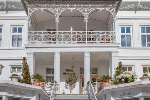 ein weißes Gebäude mit einem Balkon mit Topfpflanzen in der Unterkunft Villa Granitz Wind & Wolke in Ostseebad Sellin