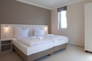 Schlafzimmer mit einem Bett mit weißer Bettwäsche und einem Fenster in der Unterkunft die Strandhäuser - Leuchtfeuer in Ostseebad Sellin