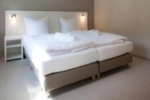 ein großes Bett mit weißer Bettwäsche und Kissen darauf in der Unterkunft die Strandhäuser - Leuchtfeuer in Ostseebad Sellin