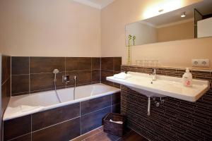 ein Badezimmer mit einer Badewanne, einem Waschbecken und einem Spiegel in der Unterkunft die Strandhäuser - Leuchtfeuer in Ostseebad Sellin
