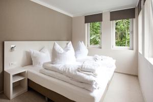 um quarto branco com uma cama com almofadas brancas em die Strandhäuser - Meeresrauschen em Ostseebad Sellin