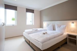 a bedroom with a large white bed with a dog laying on it at die Strandhäuser - Meeresrauschen in Ostseebad Sellin