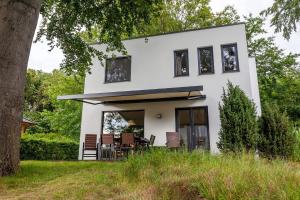 uma casa branca com janelas pretas e uma árvore em die Strandhäuser - Wolkenlos em Ostseebad Sellin
