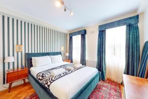 a bedroom with a blue and white bed and windows at 3 bedroom Family Friendly Apartment in Hillcrest in London