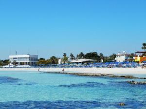 a beach with chairs and people in the water at Dome Beach Marina Hotel & Resort in Ayia Napa