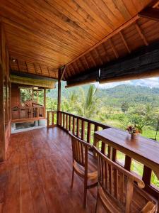 una terraza de madera con mesa y sillas. en Manuk Dewata Villa, en Sidemen