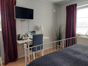 a bedroom with a bed and a desk with a television at B&B Villa Orion in Sölvesborg