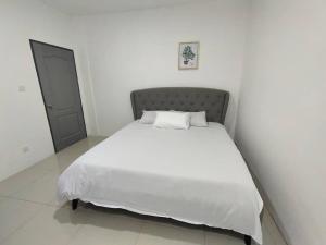 uma cama num quarto branco com uma colcha branca em CASA homestay 軒名宿 em Miri