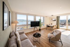 ein Wohnzimmer mit einem Sofa, Stühlen und einem TV in der Unterkunft aestate living lakeview in Horgen Zürich Zug Pfäffikon in Horgen