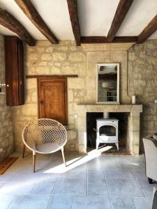 Habitación de piedra con silla y chimenea en Gîte Les Caves aux Fièvres - Maison avec jardin près de Chinon, en Beaumont-en-Véron