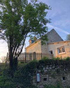 una casa de piedra con una valla y un árbol en Gîte Les Caves aux Fièvres - Maison avec jardin près de Chinon, en Beaumont-en-Véron