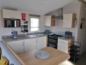 a small kitchen with a table and a stove at The Beach - Large decking area in Kent