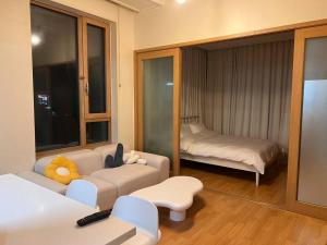 ein Wohnzimmer mit einem Sofa und einem Bett in der Unterkunft Party Room, 1min to Suwon Rodeo Street in Suwon