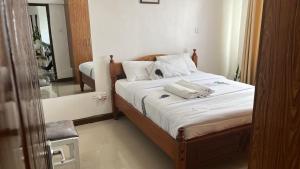um quarto com uma cama com lençóis brancos e um espelho em Kings Millennium Apartments- 3Bdrm Aprt, All Ensuite, 7km to JKI Airport, 7km to CBD em Nairobi