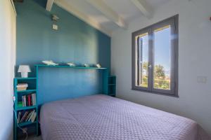 a bedroom with a blue bed and a window at Azura Prugna - Maison avec piscine partagée in Grosseto-Prugna +9 photos