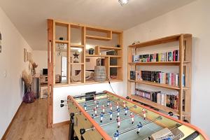 um quarto com uma mesa de matraquilhos e prateleiras de livros em La Perle de Xonrupt - Appt vue montagne em Xonrupt-Longemer