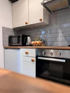 una cocina con armarios blancos y horno negro en Meadow Street Rooms, en Avonmouth