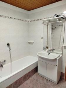 a bathroom with a tub and a sink and a bath tub at Appartamento Alla Vigna in Levico Terme