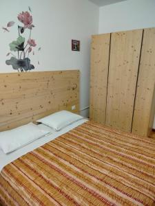 a bedroom with a bed with a wooden headboard at Appartamento Alla Vigna in Levico Terme