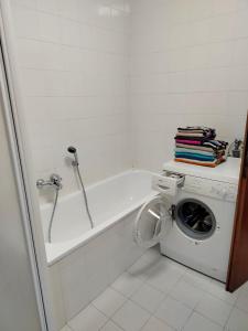 y baño con bañera blanca y lavadora. en Appartamento Alla Vigna, en Levico Terme