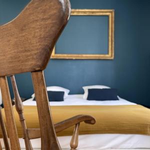 a wooden chair in front of a bed with a mirror at Suite Lavarande by La Boîte En Plus in Senlis