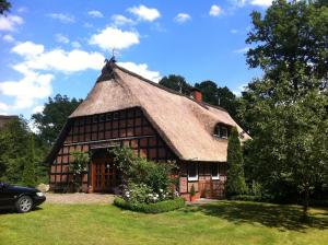 ein Haus mit einem Strohdach und einem Auto vor dem Haus in der Unterkunft Ostehof Weertzen in Weertzen