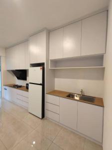 cocina con armarios blancos, fregadero y nevera en CASA homestay 軒名宿 en Miri