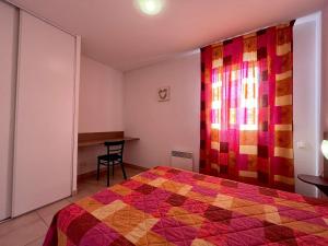 a bedroom with a bed with a colorful quilt at Appartement Gruissan, 2 pièces, 4 personnes - FR-1-229-372 in Gruissan