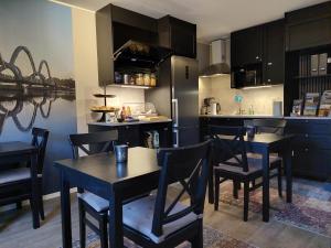 una cocina con armarios negros, mesa y sillas en B&B Villa Orion, en Sölvesborg