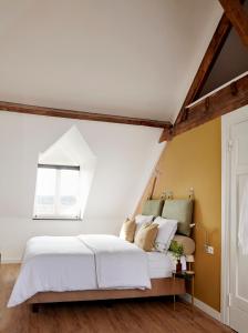 a bedroom with a white bed and a window at La Dominotte Arcen in Arcen
