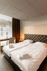 a large white bed in a room with a desk at Los Lorentes Hotel Bern Airport in Belp