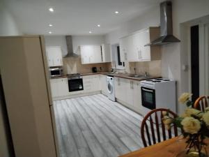 a kitchen with white cabinets and a wooden floor at Large Double Room Private Bathroom And SmartTV 8 in Barking