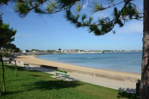 a beach with two benches and the water at Hôtel La Galiote en Ré in La Flotte