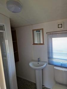a bathroom with a white sink and a toilet at Cedars Southview, Skegness in Skegness