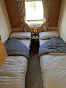 three beds in a room with a window at Cedars Southview, Skegness in Skegness