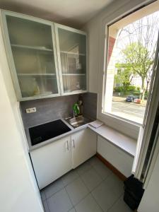 Una pequeña cocina con fregadero y ventana. en Studio Proche Paris, en Chaville